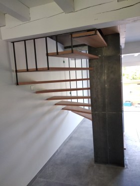 Escalier fer/bois demi tournant suspendu / Marches hêtre vernis / Bibliothèque fer brut patiné / Suspension fer plat brut patiné