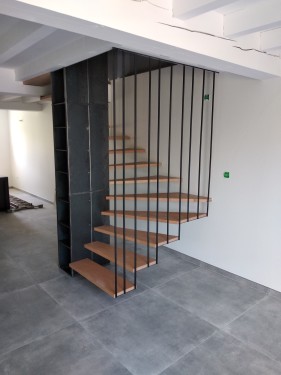 Escalier fer/bois demi tournant suspendu / Marches hêtre vernis / Bibliothèque fer brut patiné / Suspension fer plat brut patiné