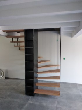 Escalier fer/bois demi tournant suspendu / Marches hêtre vernis / Bibliothèque fer brut patiné / Suspension fer plat brut patiné