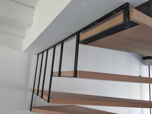 Escalier fer/bois demi tournant suspendu / Marches hêtre vernis / Bibliothèque fer brut patiné / Suspension fer plat brut patiné