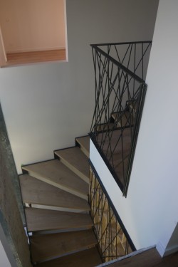 Escalier quart tournant / limon crémaillère fer brut patiné / marches chêne / garde corps bibliothèque toile d'araignée
