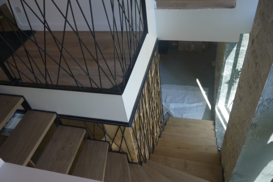 Escalier quart tournant / limon crémaillère fer brut patiné / marches chêne / garde corps bibliothèque toile d'araignée