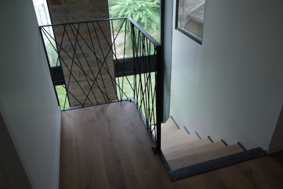 Escalier quart tournant / limon crémaillère fer brut patiné / marches chêne / garde corps bibliothèque toile d'araignée